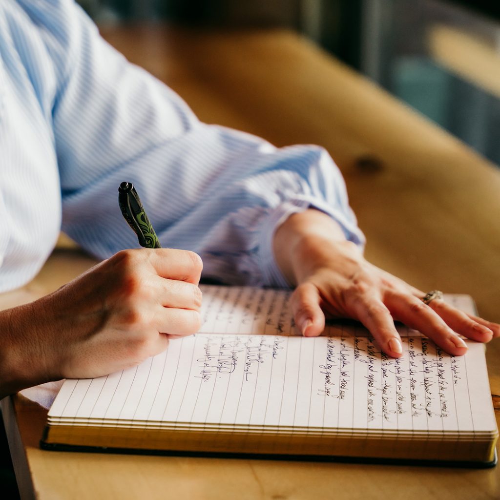 Close-up of Wren's hands writing in a notebook